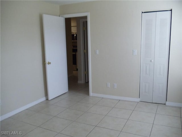 unfurnished bedroom with a closet, baseboards, and light tile patterned floors