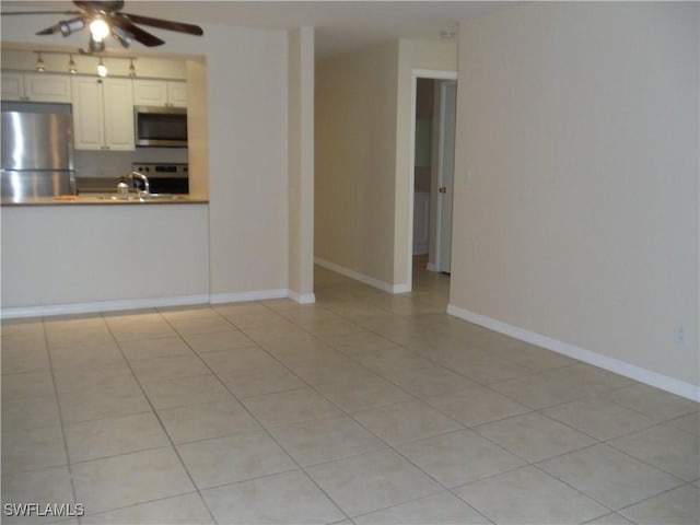 interior space featuring appliances with stainless steel finishes, white cabinets, ceiling fan, and baseboards