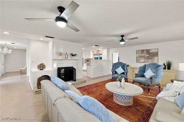 tiled living room with ceiling fan with notable chandelier