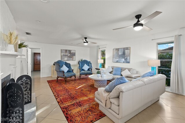 tiled living room with a fireplace and ceiling fan