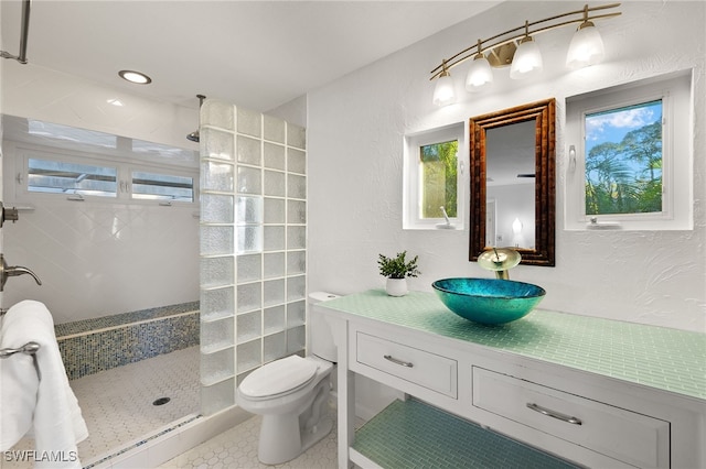 bathroom with a tile shower, vanity, and toilet