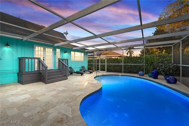 pool at dusk featuring a lanai and a patio area