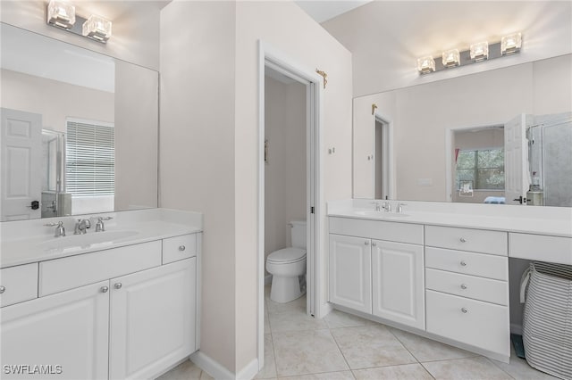 bathroom featuring tile patterned flooring, vanity, toilet, and a shower with door