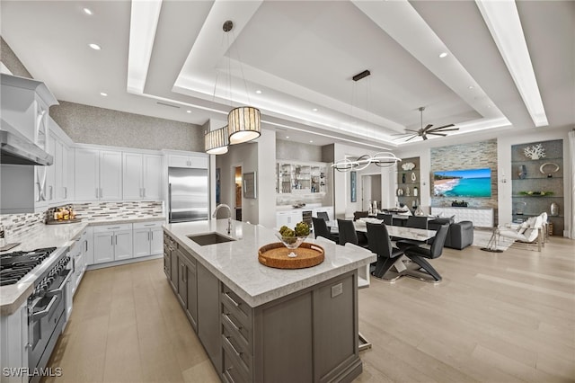 kitchen featuring a large island, high quality appliances, white cabinets, and a tray ceiling