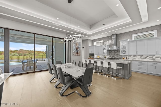 dining area featuring light hardwood / wood-style floors and a tray ceiling