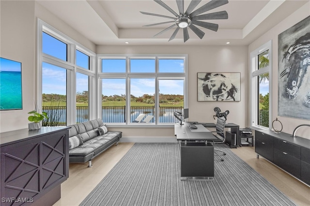 interior space featuring a water view, a tray ceiling, and ceiling fan