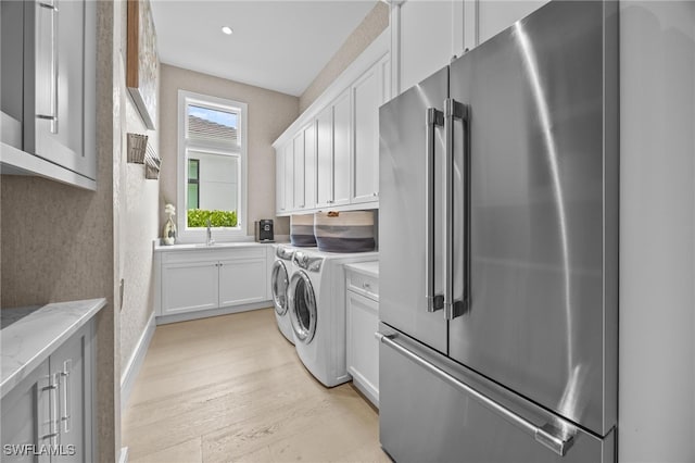 laundry area featuring light hardwood / wood-style floors, cabinets, and washer and clothes dryer