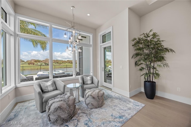 living area with light hardwood / wood-style flooring, a notable chandelier, and a water view