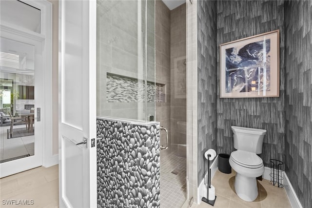 bathroom featuring toilet, a shower with shower door, and tile patterned floors