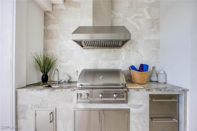 kitchen featuring wall chimney exhaust hood, decorative backsplash, and light stone countertops