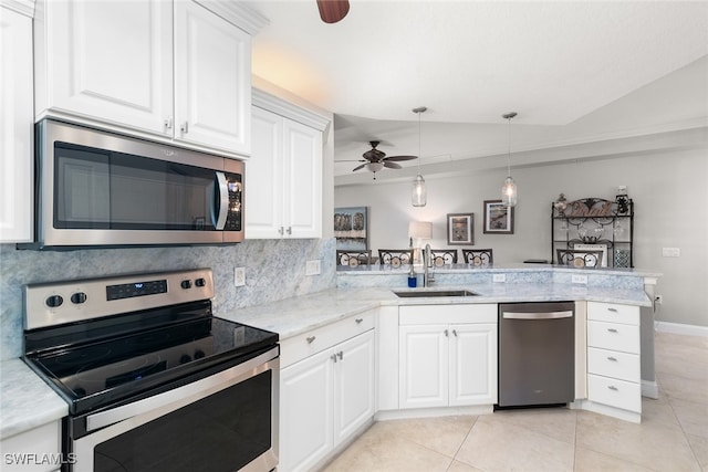 kitchen with kitchen peninsula, lofted ceiling, white cabinetry, sink, and stainless steel appliances