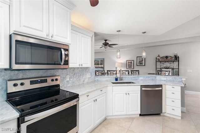 kitchen with a peninsula, ceiling fan, a sink, appliances with stainless steel finishes, and light tile patterned floors