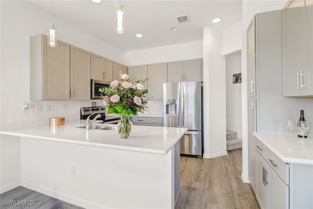 kitchen featuring stainless steel appliances, kitchen peninsula, pendant lighting, light hardwood / wood-style floors, and gray cabinets