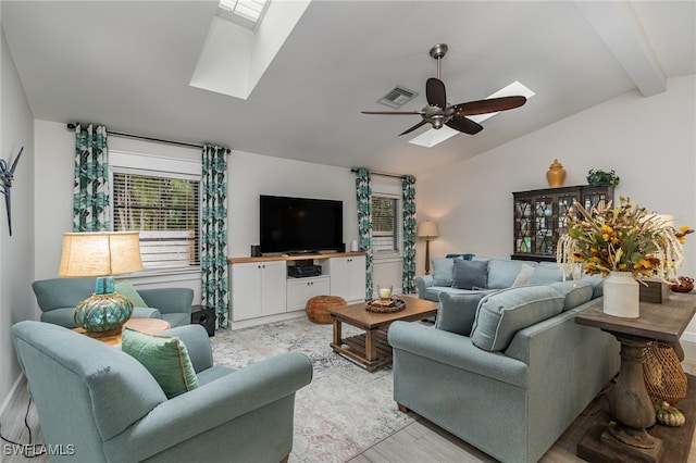 living room with ceiling fan, light hardwood / wood-style floors, and lofted ceiling with skylight