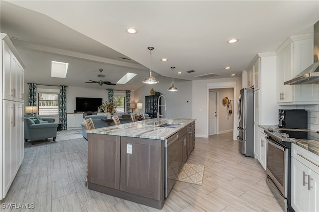 kitchen featuring light stone countertops, white cabinetry, an island with sink, and stainless steel appliances