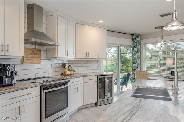 kitchen featuring white cabinetry, stainless steel electric range oven, beverage cooler, and wall chimney exhaust hood