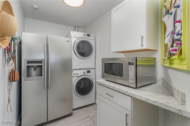 laundry room featuring stacked washing maching and dryer and light hardwood / wood-style floors