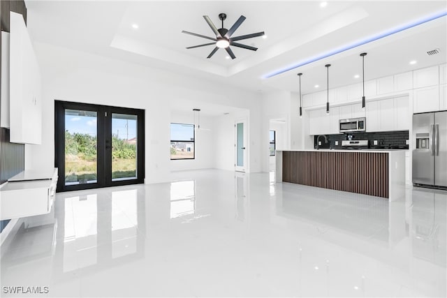 kitchen featuring a kitchen island, appliances with stainless steel finishes, hanging light fixtures, and a tray ceiling