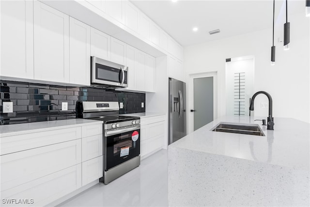 kitchen featuring tasteful backsplash, sink, white cabinetry, stainless steel appliances, and light stone counters