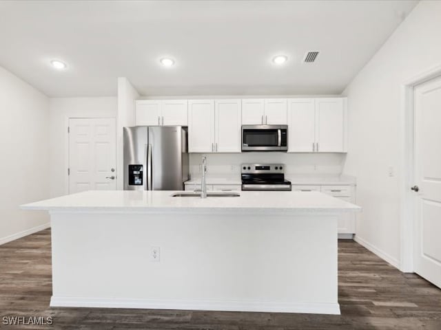 kitchen with dark wood-type flooring, stainless steel appliances, a center island with sink, sink, and white cabinets