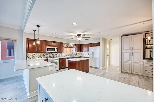 kitchen featuring tasteful backsplash, light hardwood / wood-style flooring, pendant lighting, white appliances, and a kitchen island