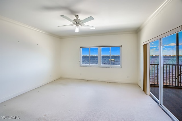 carpeted empty room with a water view, crown molding, ceiling fan, and a healthy amount of sunlight