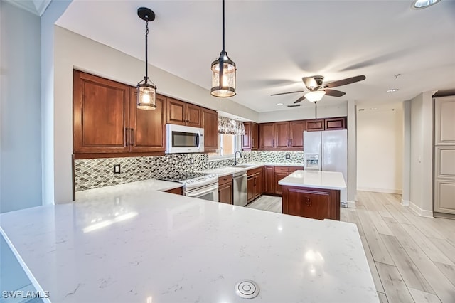 kitchen featuring kitchen peninsula, decorative backsplash, hanging light fixtures, and appliances with stainless steel finishes