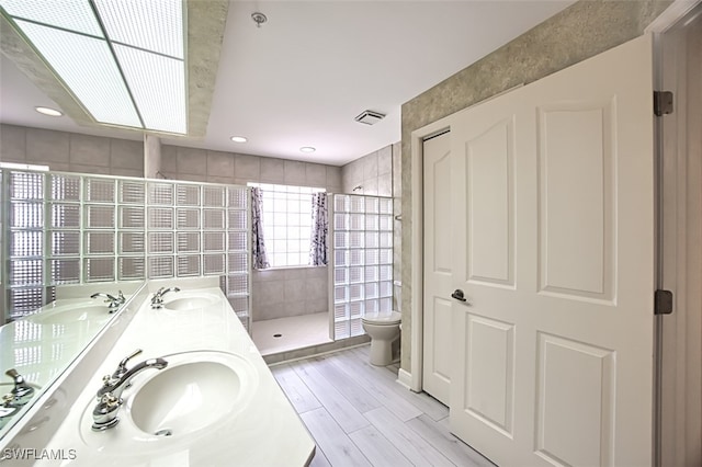 bathroom featuring vanity, toilet, wood-type flooring, and tiled shower