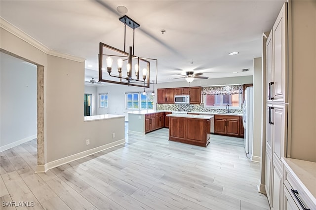 kitchen featuring ornamental molding, white appliances, decorative light fixtures, light hardwood / wood-style floors, and a kitchen island