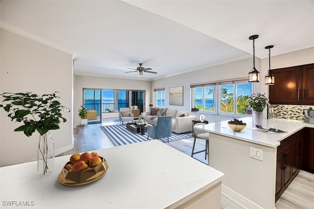 kitchen featuring tasteful backsplash, ceiling fan, hanging light fixtures, and light hardwood / wood-style floors