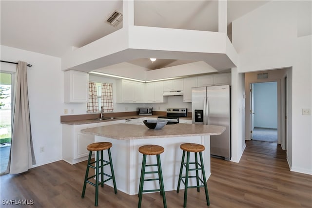 kitchen featuring a kitchen bar, appliances with stainless steel finishes, white cabinets, and dark hardwood / wood-style flooring