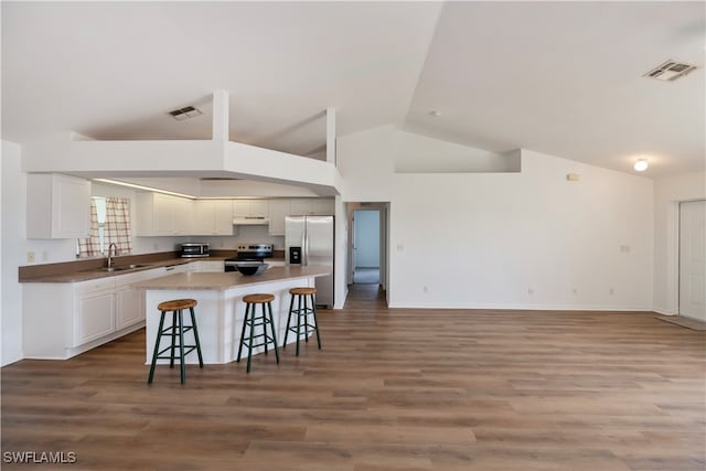 kitchen with white cabinetry, appliances with stainless steel finishes, sink, vaulted ceiling, and a kitchen breakfast bar