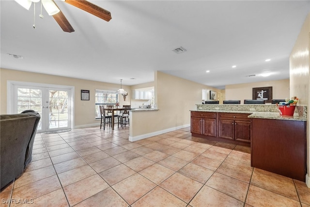 kitchen featuring kitchen peninsula, ceiling fan, light tile patterned floors, light stone countertops, and pendant lighting