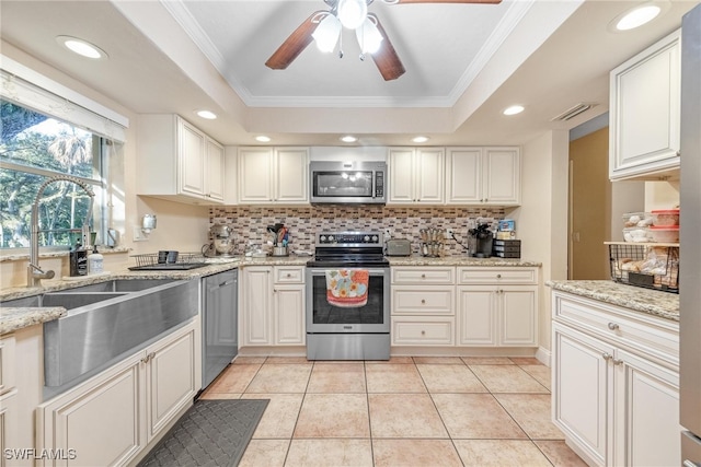 kitchen with crown molding, white cabinets, stainless steel appliances, and a tray ceiling