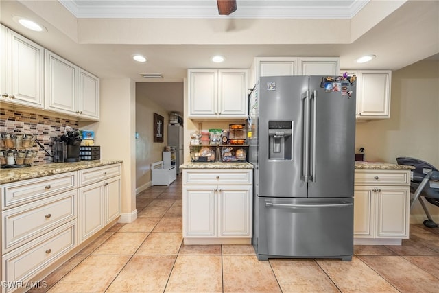 kitchen with crown molding, stainless steel fridge with ice dispenser, light tile patterned flooring, light stone counters, and tasteful backsplash