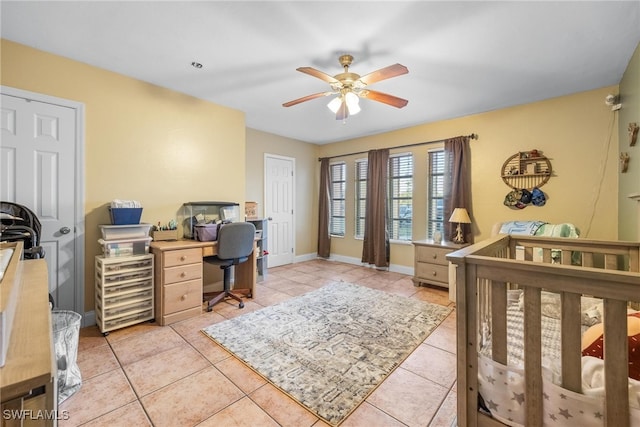 tiled bedroom featuring a closet, a nursery area, and ceiling fan