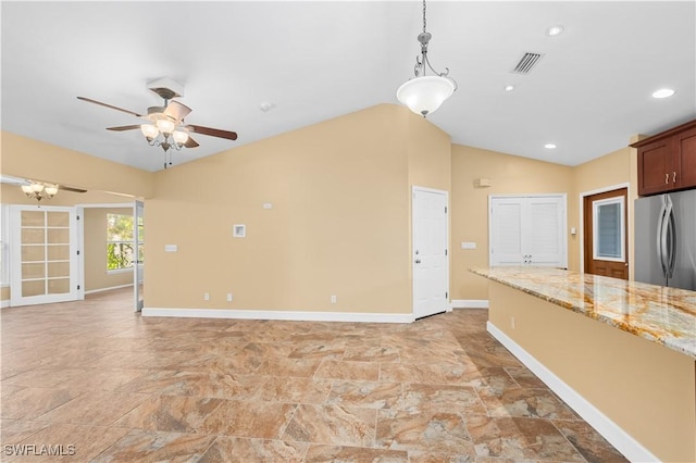 kitchen featuring vaulted ceiling, decorative light fixtures, stainless steel fridge, ceiling fan, and light stone countertops