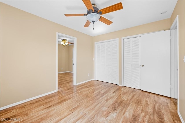 unfurnished bedroom with ceiling fan, two closets, and light wood-type flooring