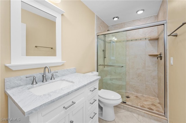 bathroom featuring a shower with door, vanity, tile patterned flooring, and toilet