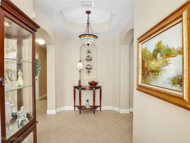 hallway with light tile patterned floors and a raised ceiling