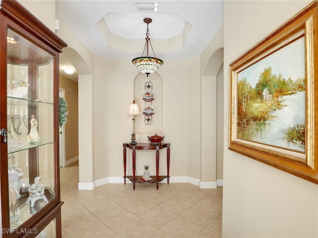 corridor featuring light tile patterned floors and a raised ceiling