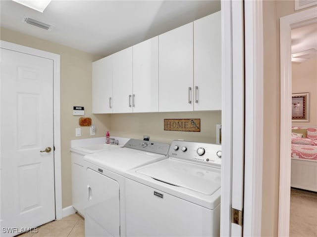 laundry area with cabinets, light tile patterned floors, sink, and independent washer and dryer