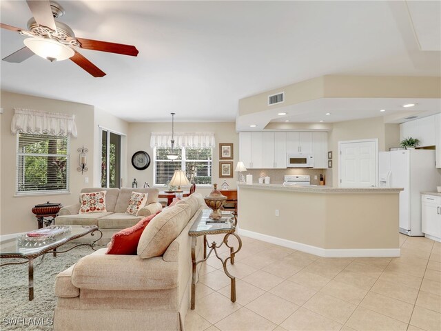 living room featuring ceiling fan with notable chandelier, a wealth of natural light, and light tile patterned flooring