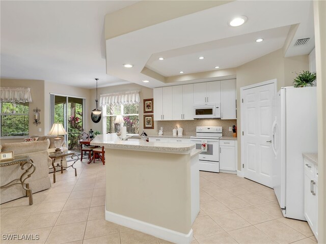 kitchen with white cabinetry, backsplash, hanging light fixtures, white appliances, and a kitchen island with sink