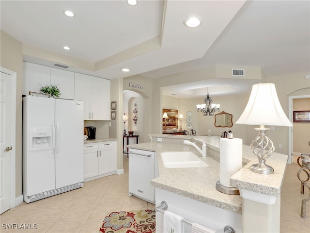 kitchen featuring white cabinetry, a notable chandelier, pendant lighting, sink, and white appliances