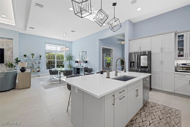 kitchen featuring white cabinetry, sink, stainless steel appliances, and a center island with sink