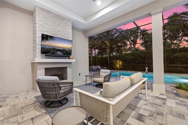 view of patio with a lanai and an outdoor stone fireplace