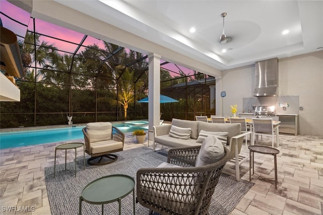 patio terrace at dusk featuring outdoor lounge area, a pool with hot tub, a lanai, and exterior kitchen