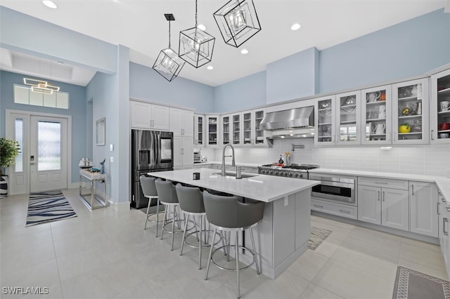 kitchen featuring backsplash, wall chimney exhaust hood, stainless steel appliances, sink, and white cabinets