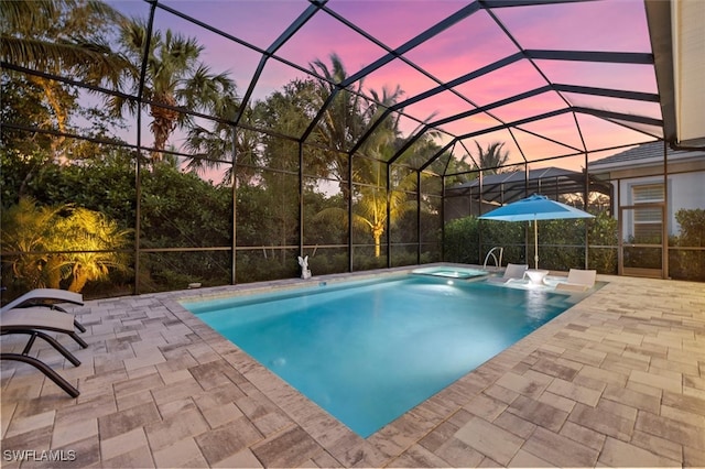 pool at dusk with an in ground hot tub, a patio, and a lanai